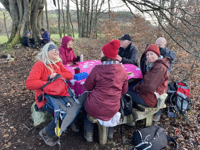 A group of people sitting at a picnic table on their way from Kemnay to Monymusk