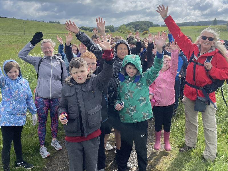 The children of Maud primary school waving while walking up a hill