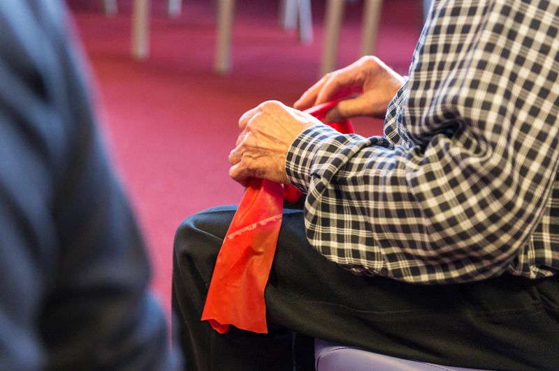 Image shows a man sitting with an exercise band on his knee