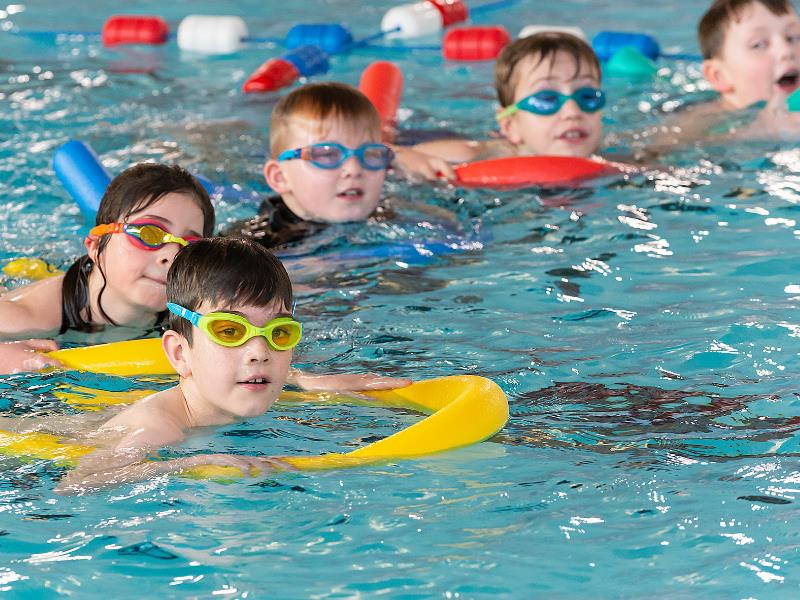 A group of children holding floats in the swimming pool