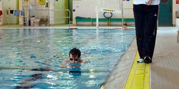 A adult swimming a length of the pool holding a float