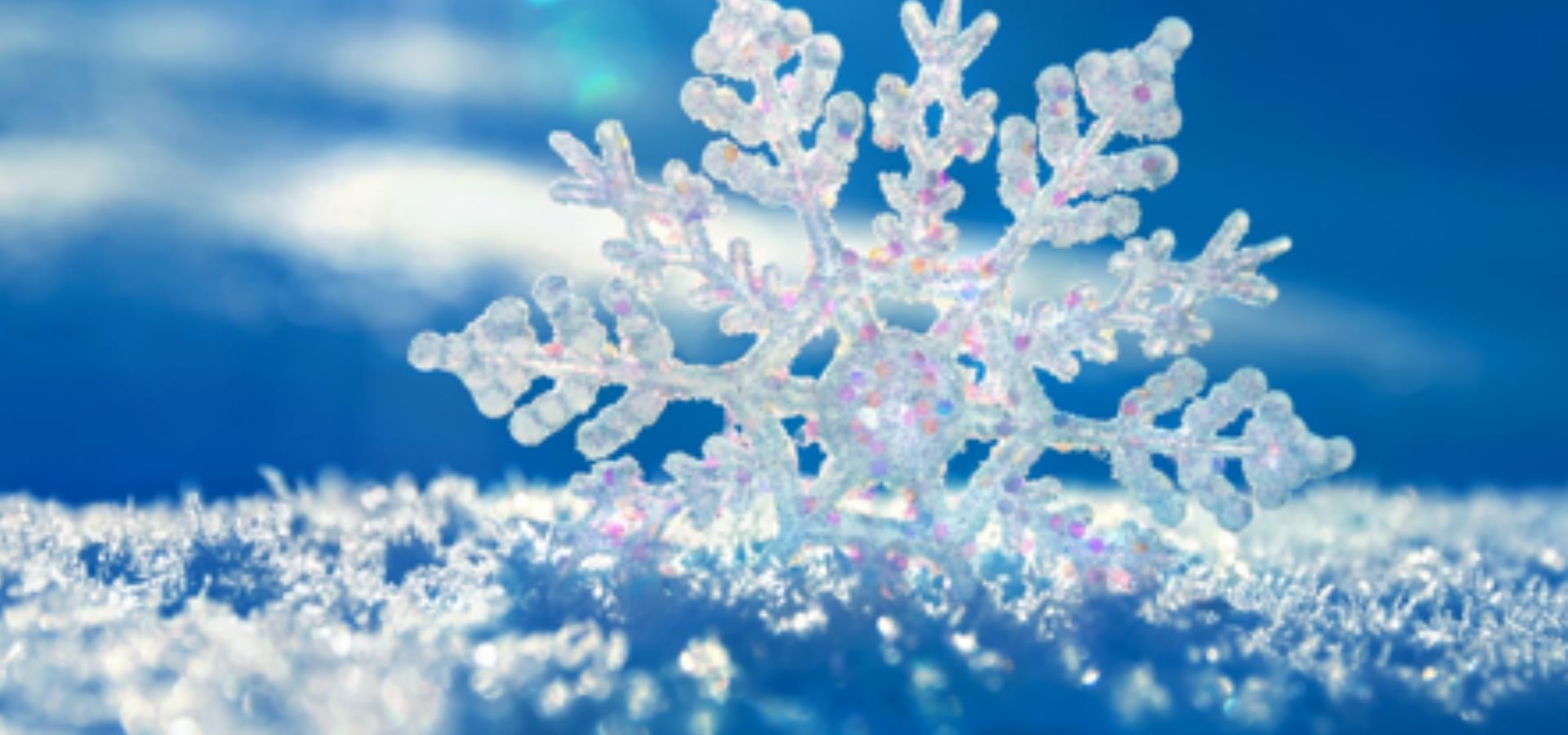 A close up of a snow flake with a blue ski behind it