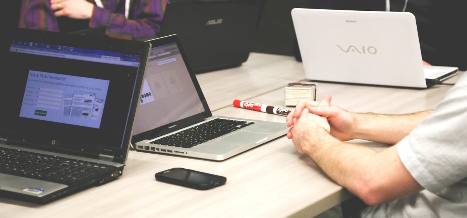 A group of people around a desk with laptops