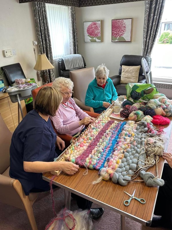 Two residents of Ythanvale Home work with a selection of wool