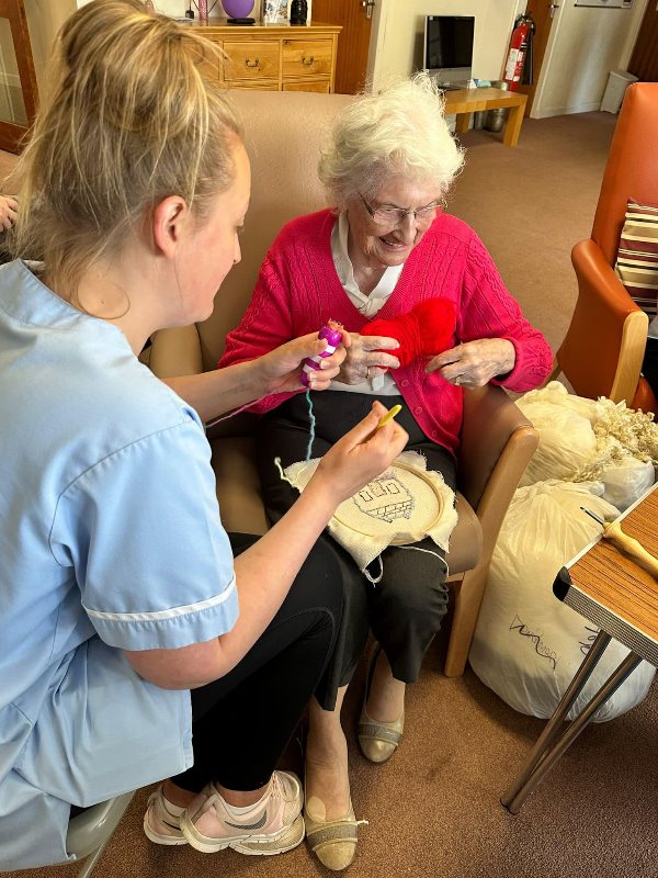 A care worker helps a resident with a tapestry